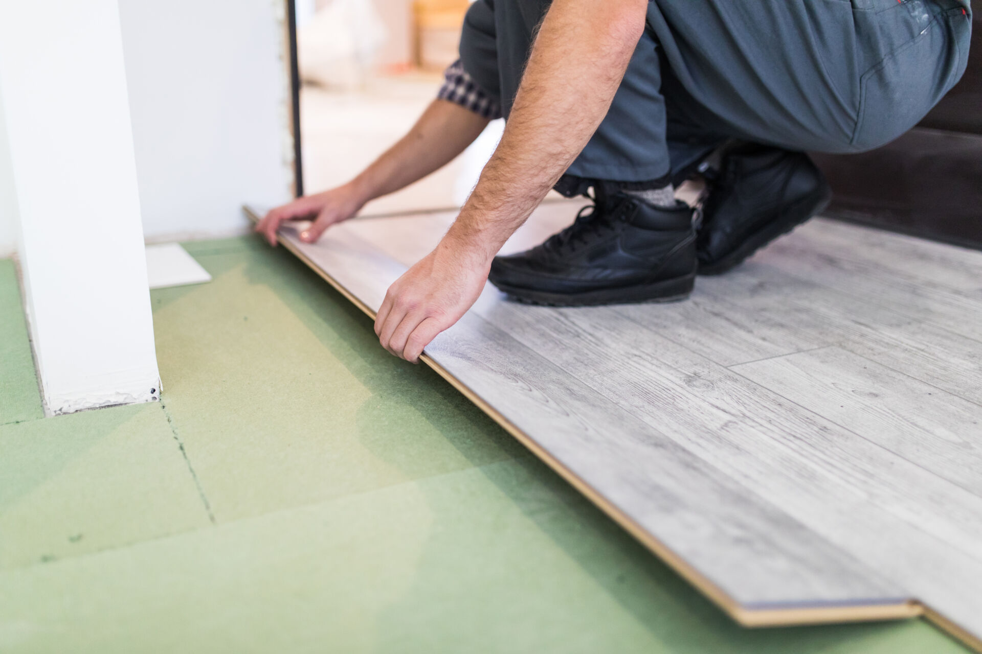 Laminate flooring being installed on top of soundproofing mute mat underneath